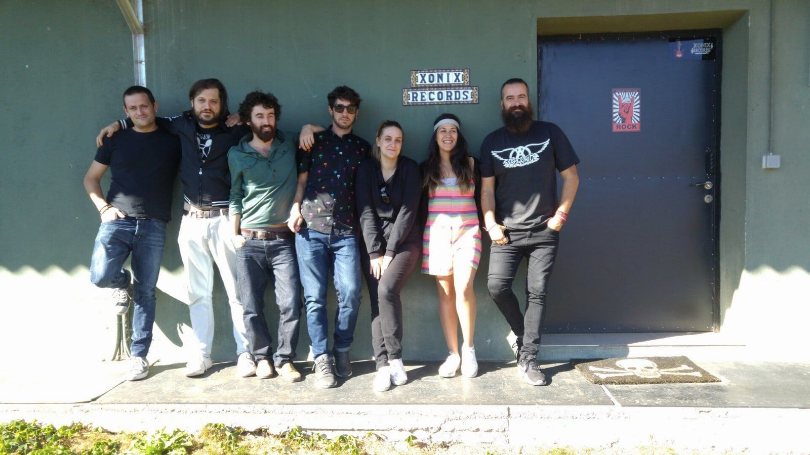 Banda posando ante la puerta del estudio, bajo el cartel de Xonix Records